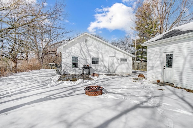 snow covered back of property featuring a fire pit