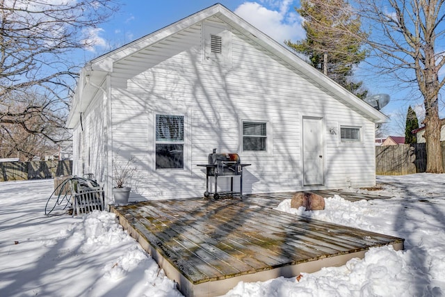 snow covered back of property with a wooden deck