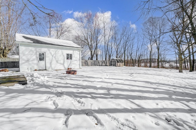 yard covered in snow with a storage shed and an outdoor fire pit