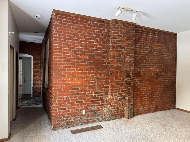 hall with carpet and brick wall