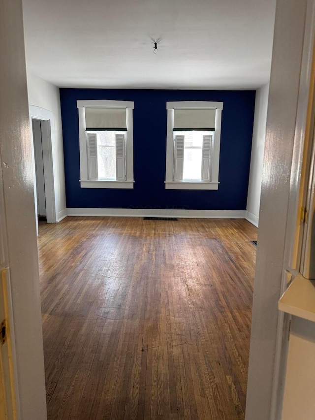 spare room with a wealth of natural light and dark hardwood / wood-style flooring