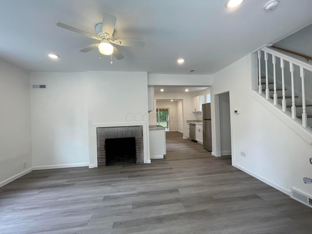 unfurnished living room with ceiling fan, hardwood / wood-style floors, and a brick fireplace