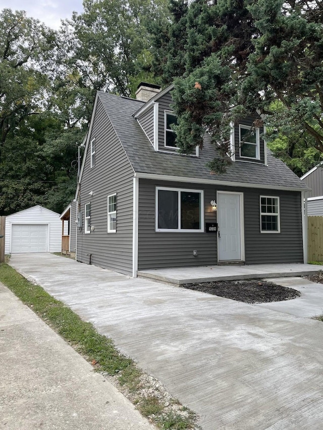 new england style home featuring a garage and an outdoor structure