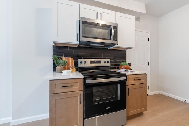 kitchen featuring white cabinets, appliances with stainless steel finishes, light wood-type flooring, and tasteful backsplash