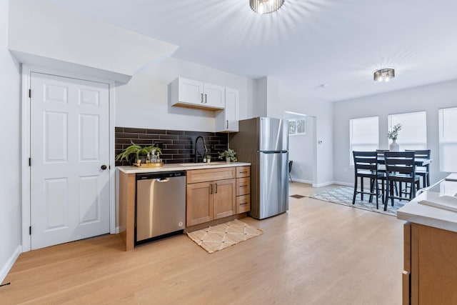 kitchen with light hardwood / wood-style floors, sink, white cabinetry, and stainless steel appliances