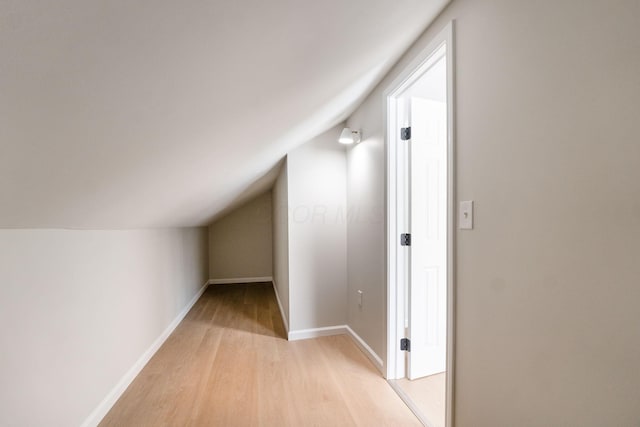 bonus room featuring light wood-type flooring and vaulted ceiling