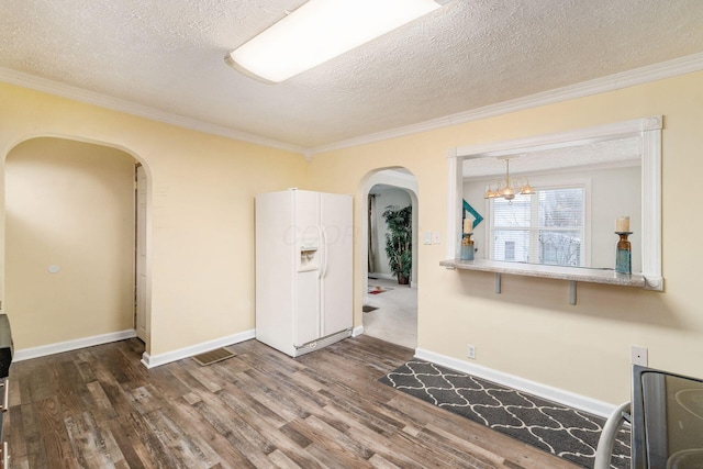 unfurnished room with crown molding, dark hardwood / wood-style floors, a textured ceiling, and a notable chandelier