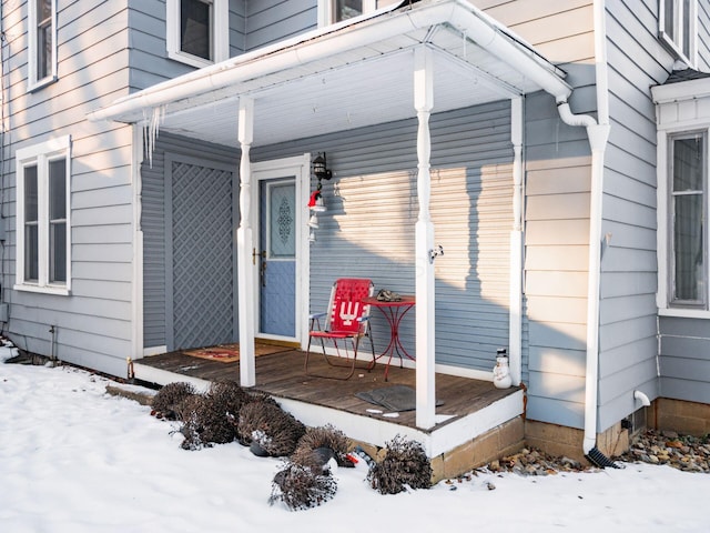 snow covered property entrance with a porch