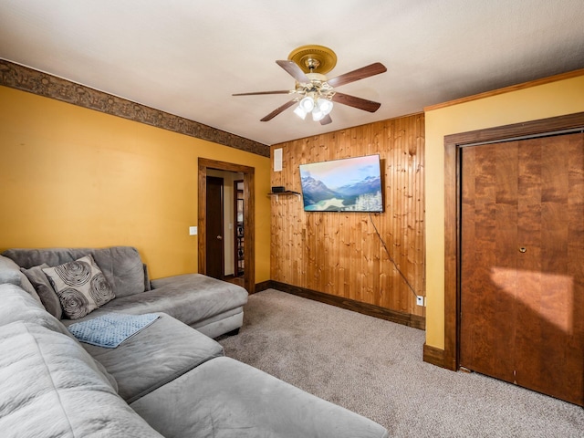 living room featuring crown molding, wood walls, carpet flooring, and ceiling fan