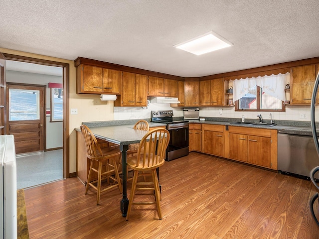 kitchen with sink, wood-type flooring, a textured ceiling, and appliances with stainless steel finishes