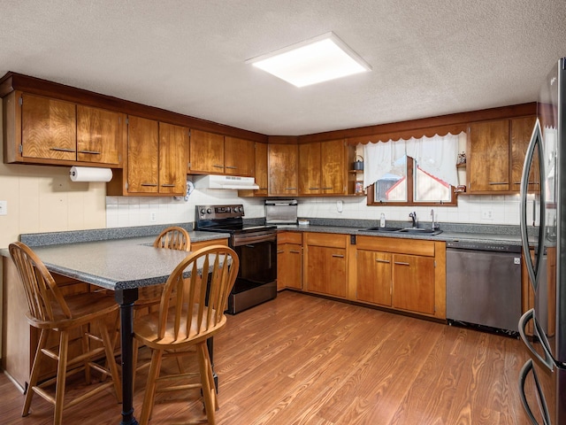 kitchen featuring hardwood / wood-style flooring, sink, a textured ceiling, and stainless steel appliances