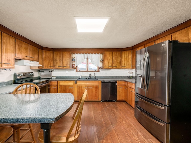 kitchen featuring sink, stainless steel appliances, light hardwood / wood-style flooring, and a textured ceiling