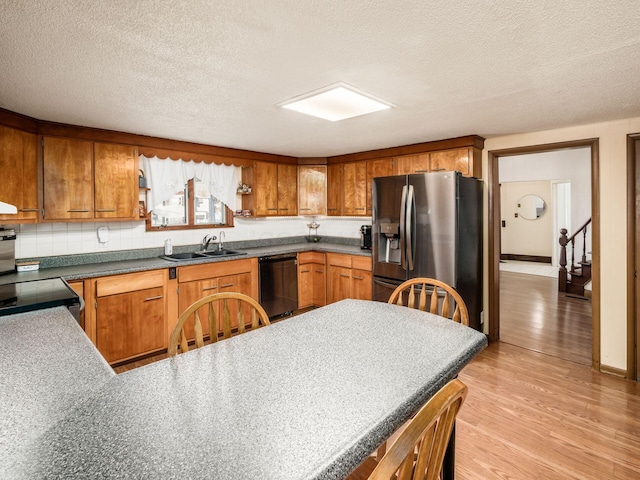 kitchen featuring sink, light hardwood / wood-style flooring, appliances with stainless steel finishes, and a textured ceiling