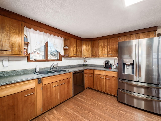 kitchen with stainless steel fridge, sink, a textured ceiling, black dishwasher, and light hardwood / wood-style floors