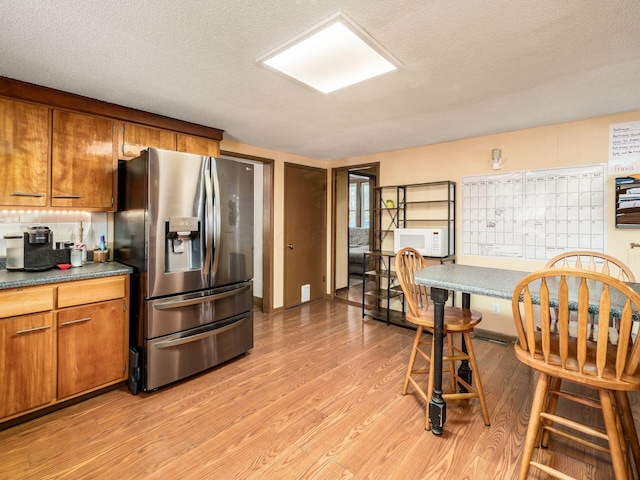 kitchen with stainless steel refrigerator with ice dispenser, light hardwood / wood-style floors, a textured ceiling, and mail boxes