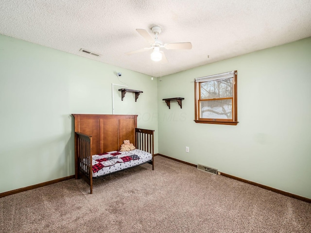 carpeted bedroom with ceiling fan and a textured ceiling