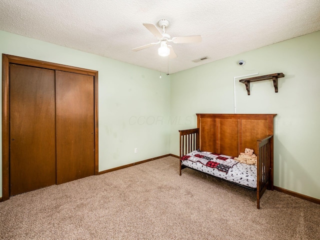 carpeted bedroom featuring a closet, ceiling fan, and a textured ceiling