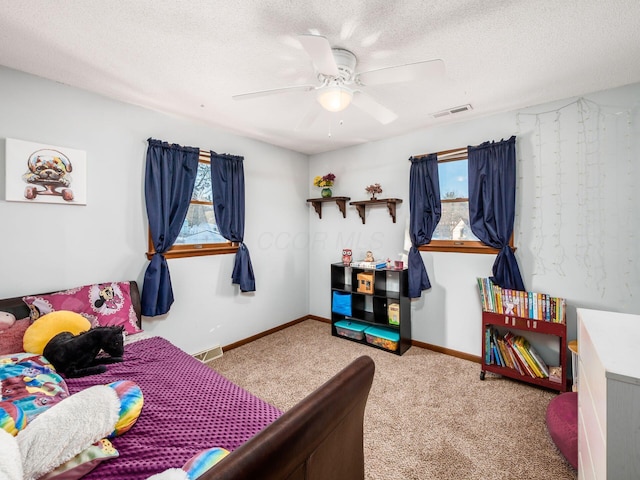 bedroom with ceiling fan, a textured ceiling, light carpet, and multiple windows