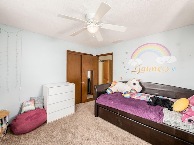 bedroom with ceiling fan, a textured ceiling, a closet, and light carpet