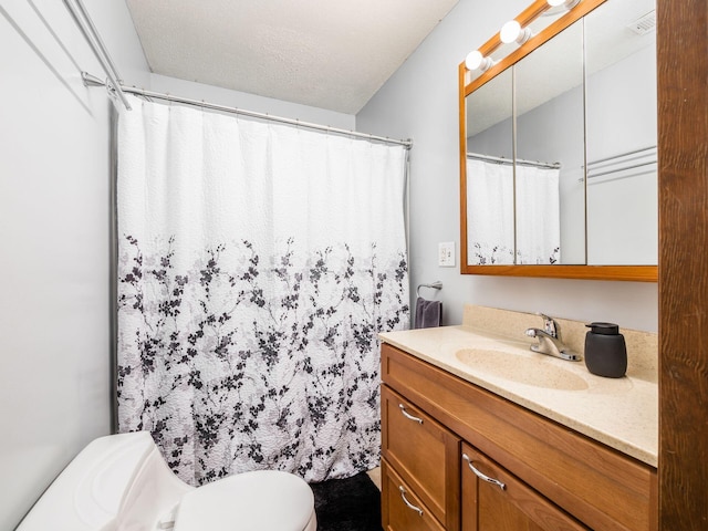 bathroom with vanity, toilet, and a textured ceiling