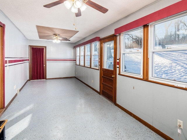 unfurnished sunroom with ceiling fan