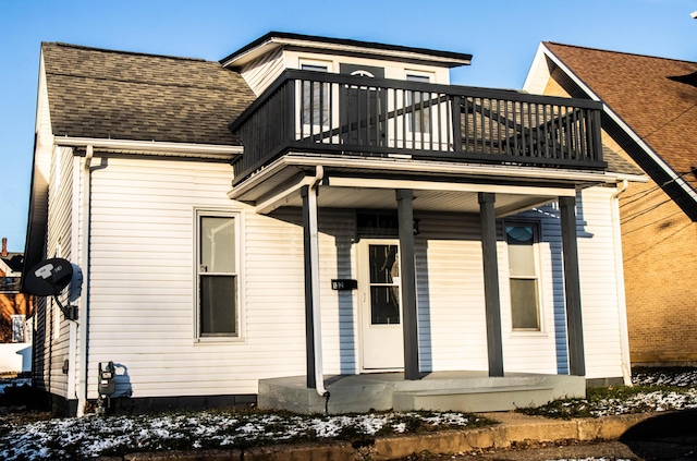 snow covered rear of property with a balcony