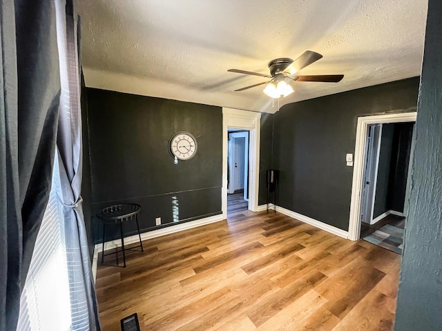 empty room featuring ceiling fan, a textured ceiling, and light hardwood / wood-style flooring