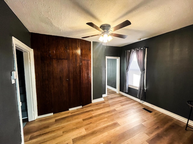 unfurnished bedroom with light wood-type flooring, a textured ceiling, a closet, and ceiling fan