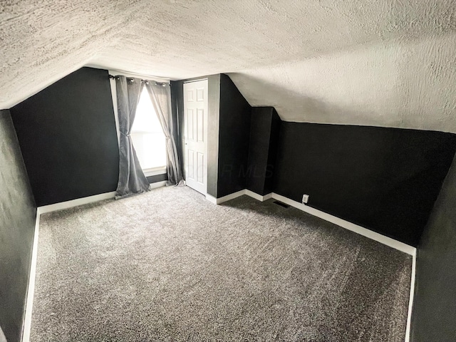 additional living space featuring carpet flooring, vaulted ceiling, and a textured ceiling