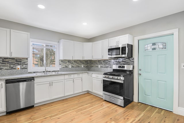 kitchen featuring light wood-type flooring, stainless steel appliances, white cabinetry, and sink