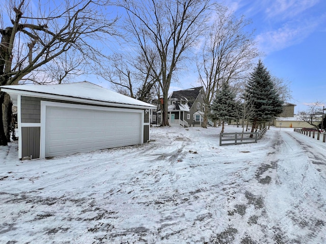 yard layered in snow featuring a garage and an outbuilding