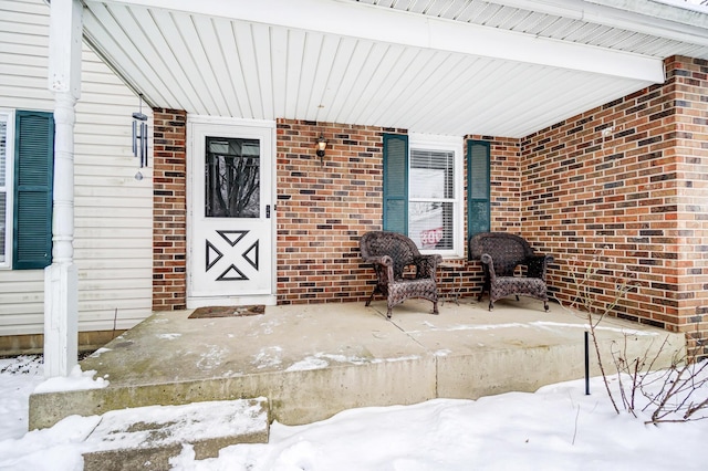 snow covered property entrance with covered porch