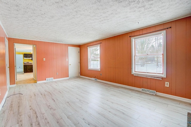 empty room featuring light hardwood / wood-style floors and wood walls