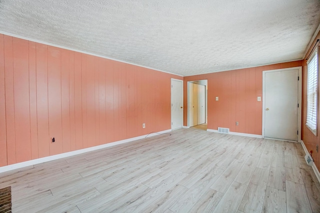 unfurnished room featuring light wood-type flooring and wood walls