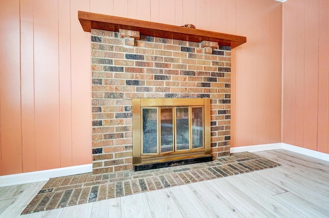 interior details featuring a brick fireplace, hardwood / wood-style flooring, and wooden walls