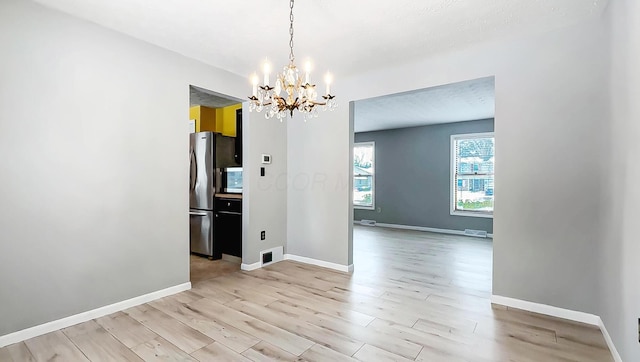 unfurnished dining area featuring a chandelier and light hardwood / wood-style floors