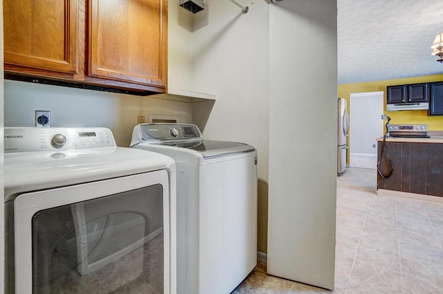 laundry room featuring a textured ceiling, cabinets, light tile patterned flooring, and independent washer and dryer