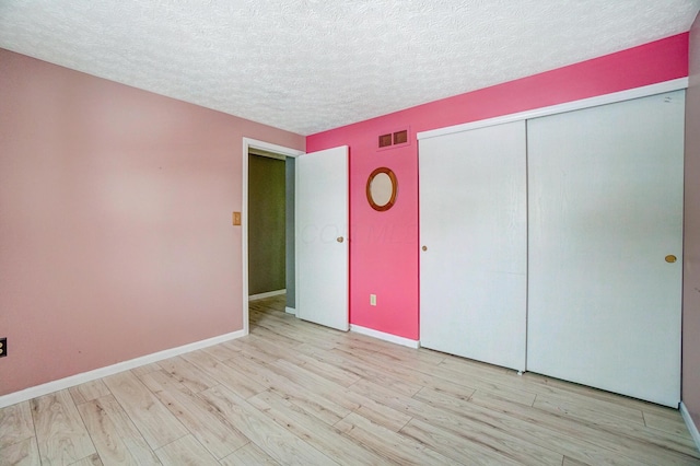 unfurnished bedroom featuring light wood-type flooring, a closet, and a textured ceiling