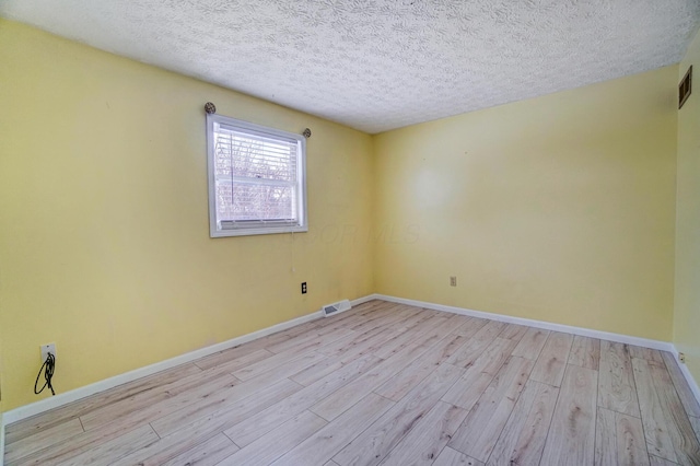 spare room with a textured ceiling and light hardwood / wood-style flooring