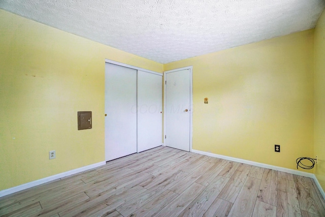 unfurnished bedroom with light wood-type flooring, a closet, and a textured ceiling