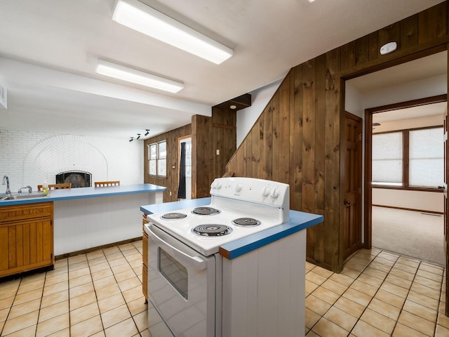 kitchen with sink, white electric stove, light tile patterned floors, and wooden walls