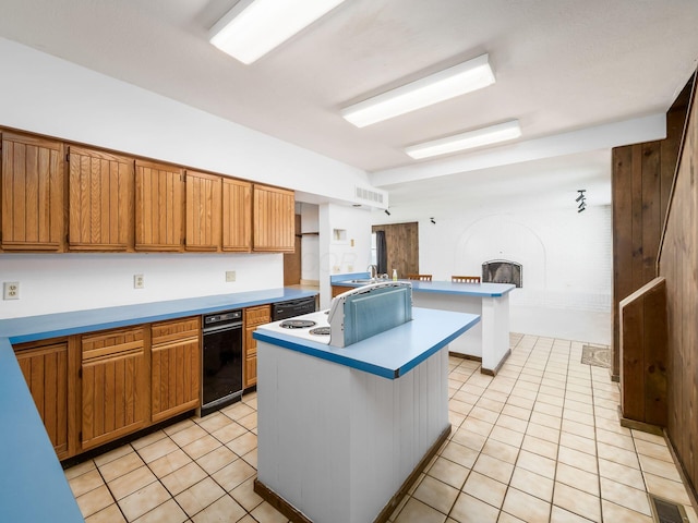 kitchen with a breakfast bar area, a fireplace, a kitchen island with sink, and light tile patterned floors