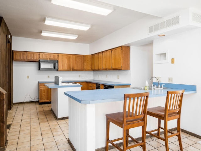 kitchen featuring sink, kitchen peninsula, light tile patterned flooring, and a kitchen bar