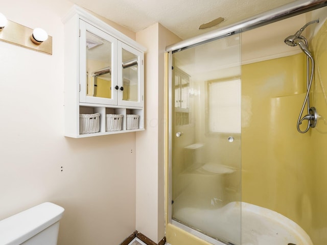 bathroom with toilet, a shower with door, and a textured ceiling