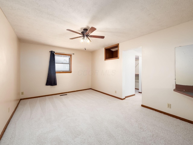 carpeted empty room featuring ceiling fan and a textured ceiling