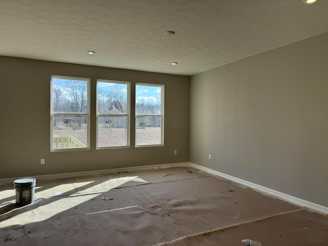 unfurnished room featuring a textured ceiling and baseboards