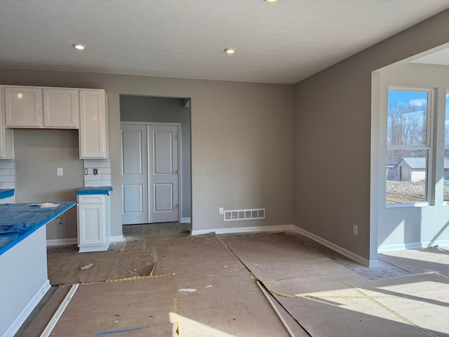 kitchen featuring baseboards, visible vents, and white cabinetry