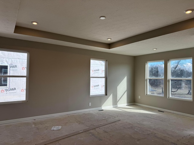 empty room with baseboards, a tray ceiling, and a healthy amount of sunlight