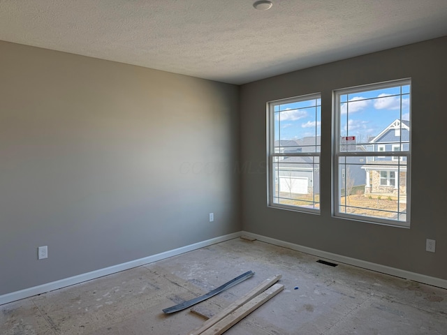 empty room featuring visible vents, baseboards, and a textured ceiling