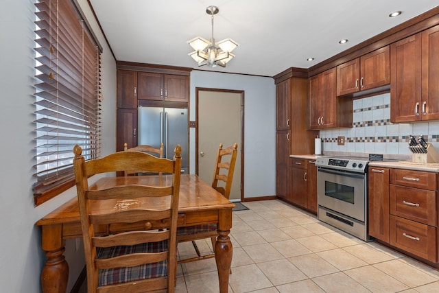 kitchen featuring a notable chandelier, backsplash, light tile patterned floors, decorative light fixtures, and stainless steel appliances